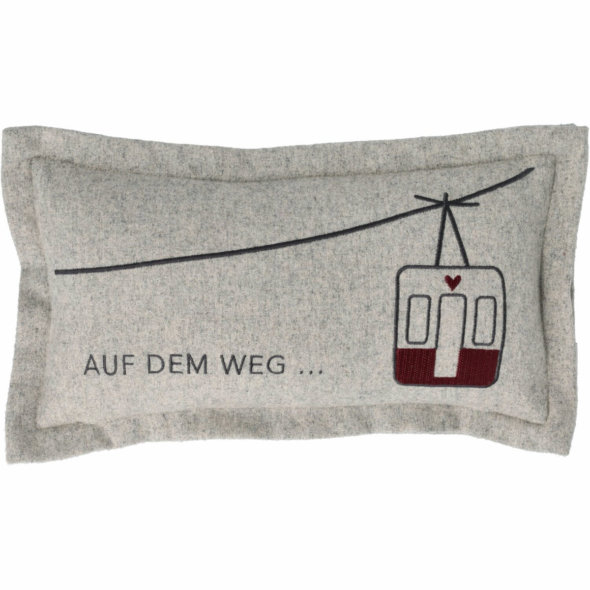 Graues Traumkissen mit Spruch „AUF DEM WEG…“ und roter Straßenbahn-Grafik