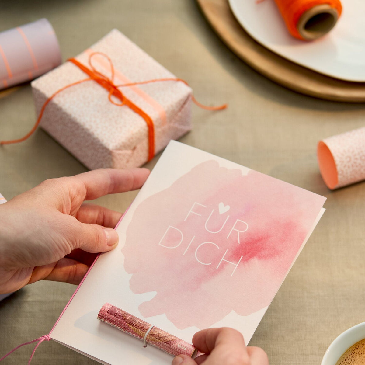 Rosa Grußkarte „FÜR DICH“ mit Aquarellblume; Person hält Karte am pinken Band
