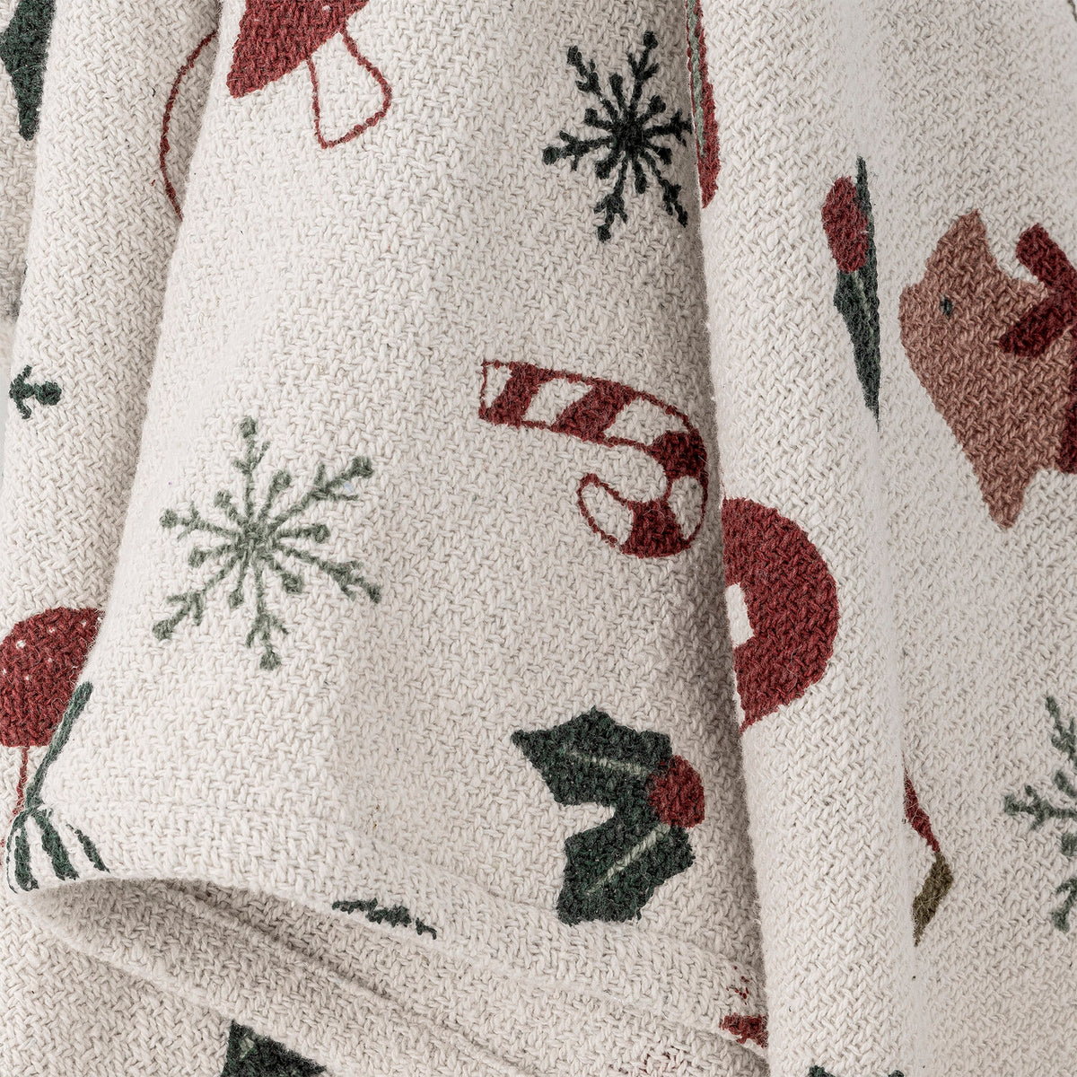 Naturfarbene Decke mit Weihnachtsmotiven wie Schneeflocken, Geschenken und Kugeln