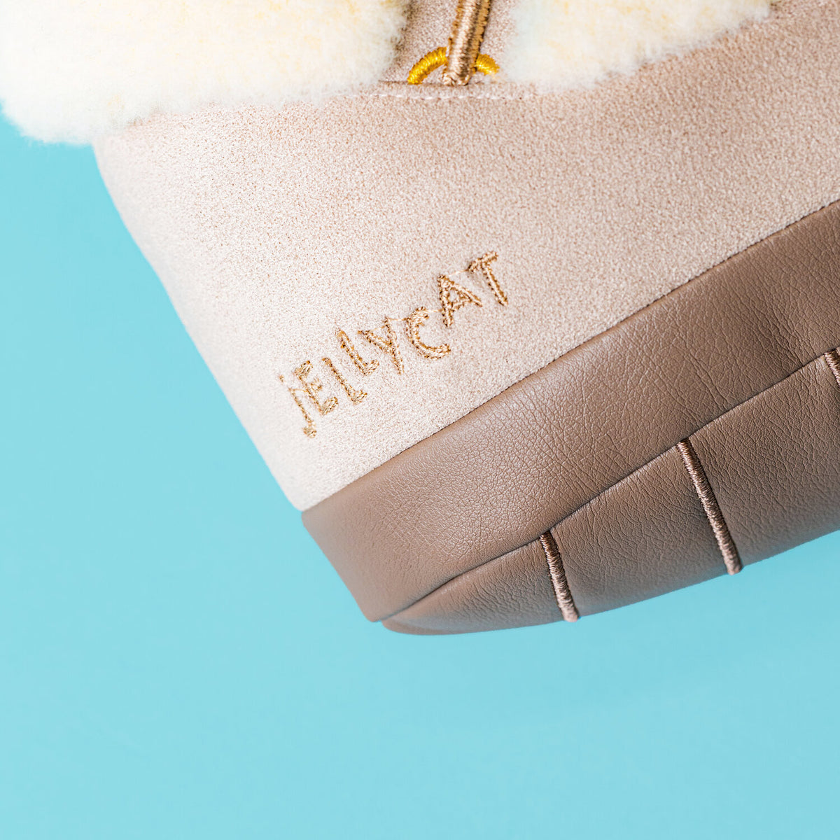 Nahaufnahme: bestickter Schriftzug „Jellycat“ am beigen Plüschschuh