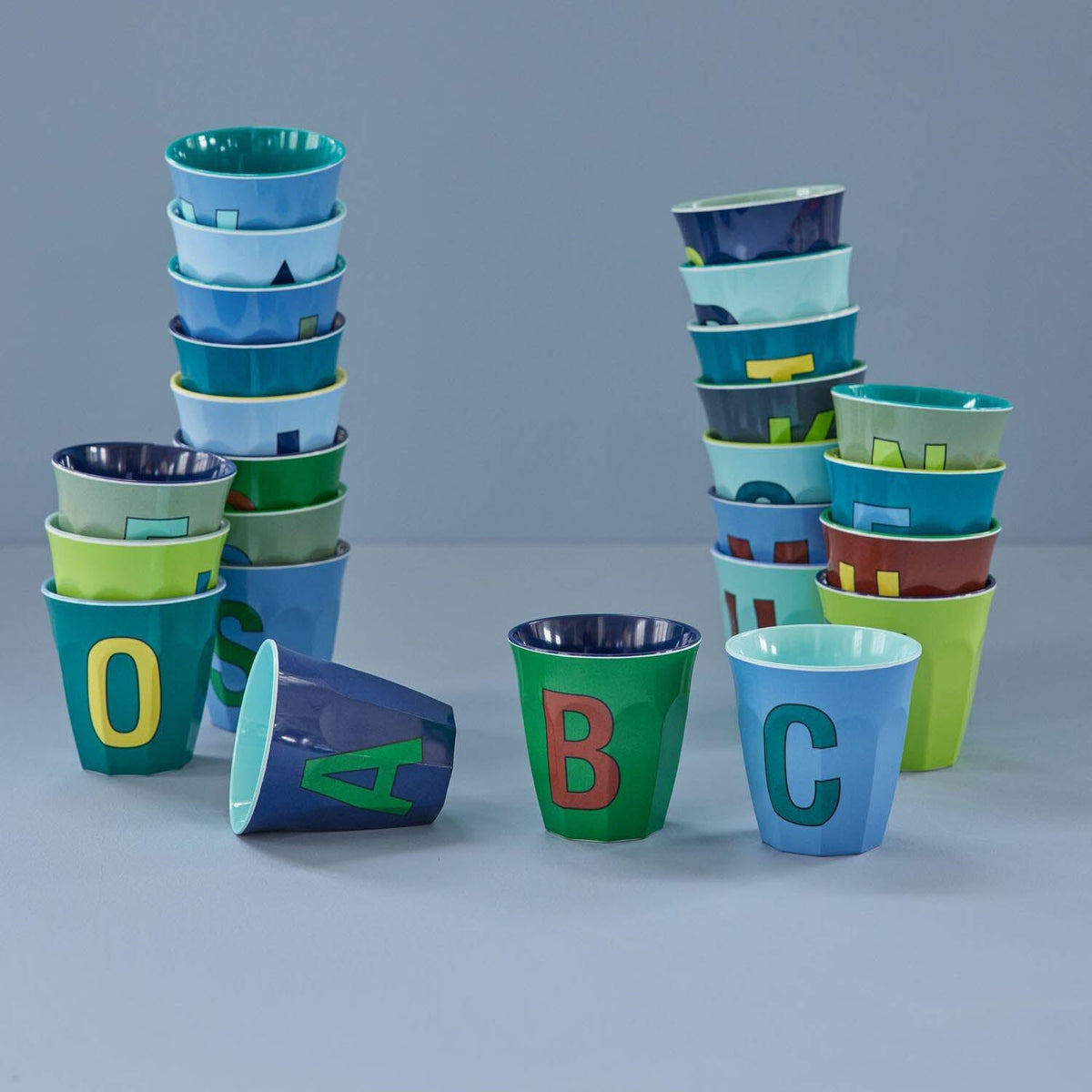 Mehrere Buchstaben-Becher, darunter dunkelblauer mit rotem Buchstaben R
