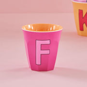 Pinkfarbener Melaminbecher mit großem Buchstaben F und gelbem Innenrand