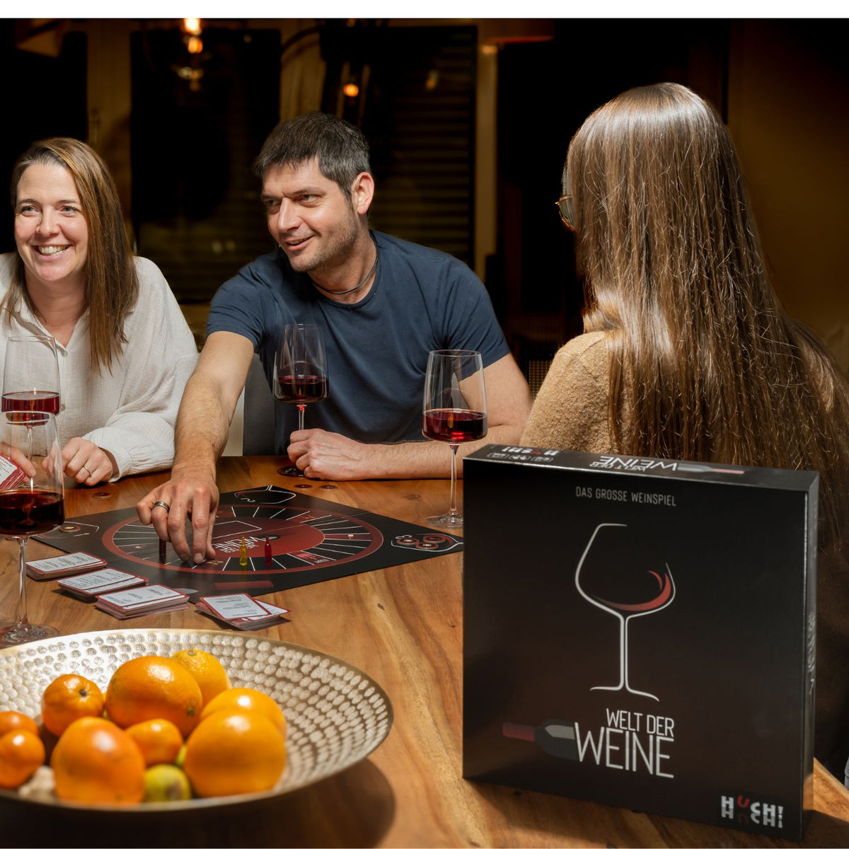 Wein-Quizspiel am Tisch mit Personen, Spielbox liegt sichtbar bereit