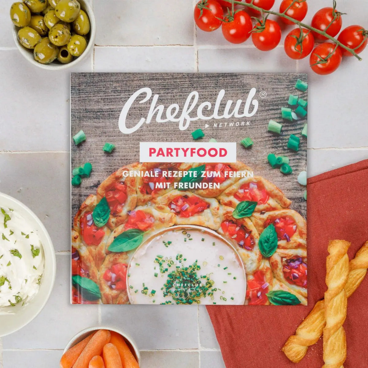 Themenkochbuch Partyfood mit Chefclub-Cover auf hellen Fliesen