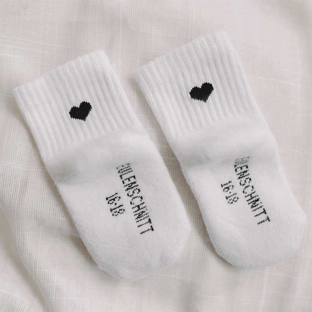 Babysocken mit schwarzem Herz und Schriftzug am Fersenbereich, weißes Paar
