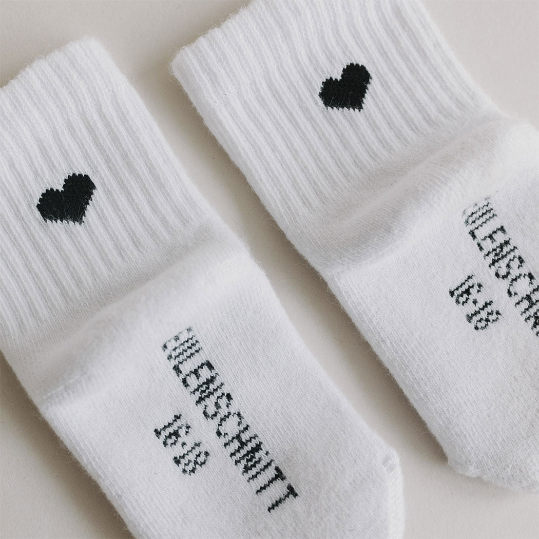 Babysocken-Detail: gerippte Struktur, schwarzes Herz und gestickte Textaufdrucke