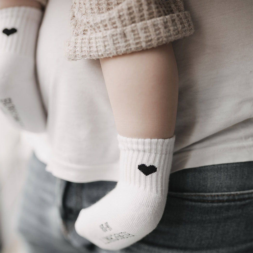 Babysocke mit Herzmotiv, weiß mit schwarzem Herz auf dem Knöchel