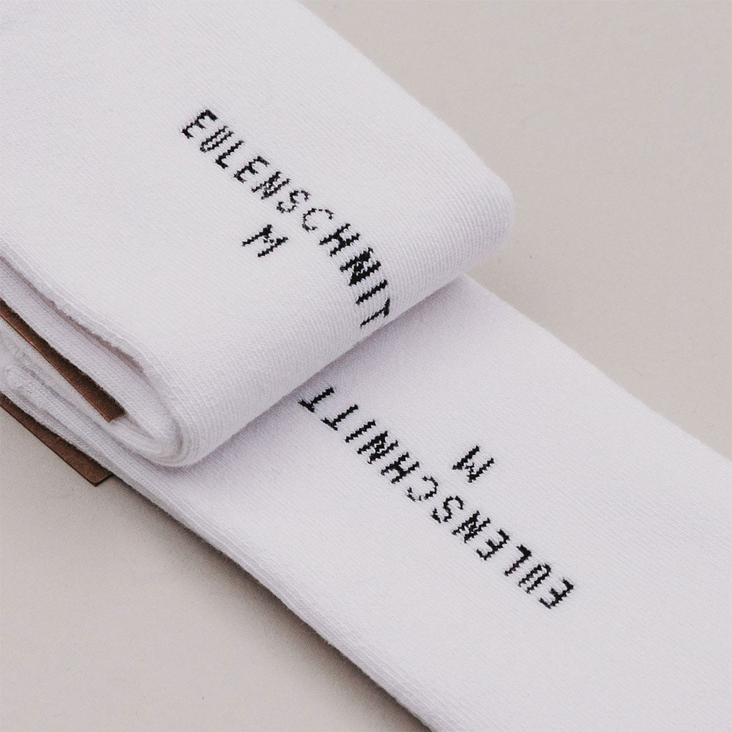 Weiße Socken im Nahdetail: gestickter Text am Bündchen.