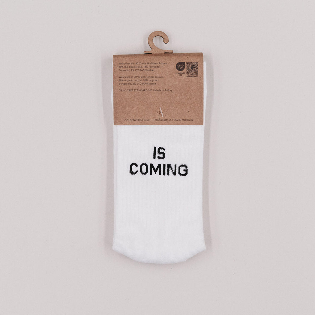 Einzelne weiße Socke mit Aufdruck „IS COMING“ am Schaft, am Hänger.