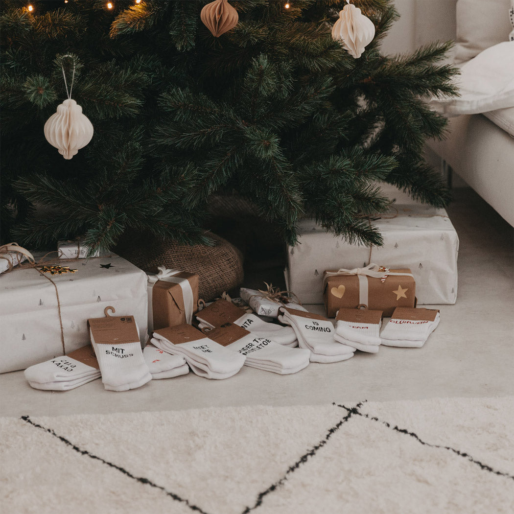 Set weiße Socken mit Aufdrucken, darunter „SANTA“ und „IS COMING“.