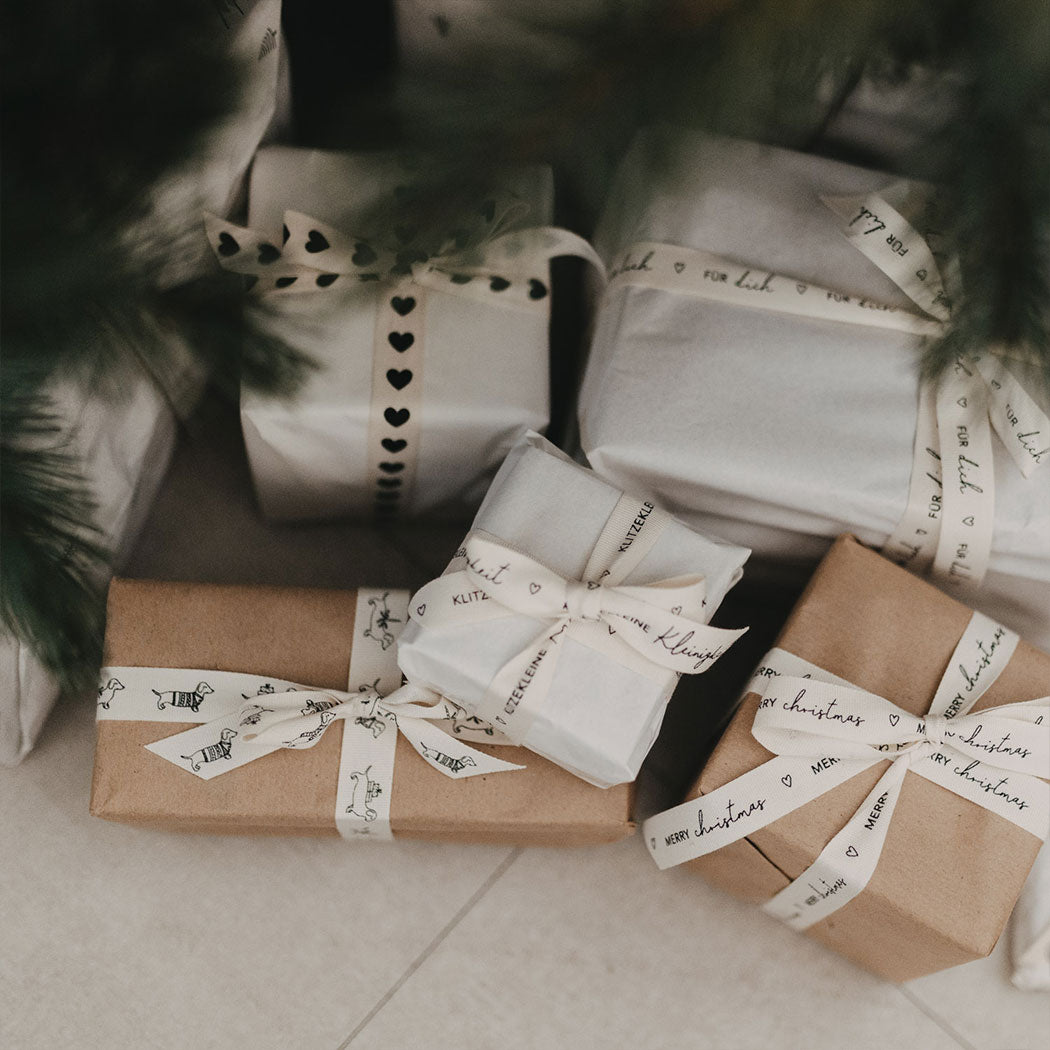 Geschenkband mit Dackelprint als Schleife an verpackten Geschenken, naturfarben