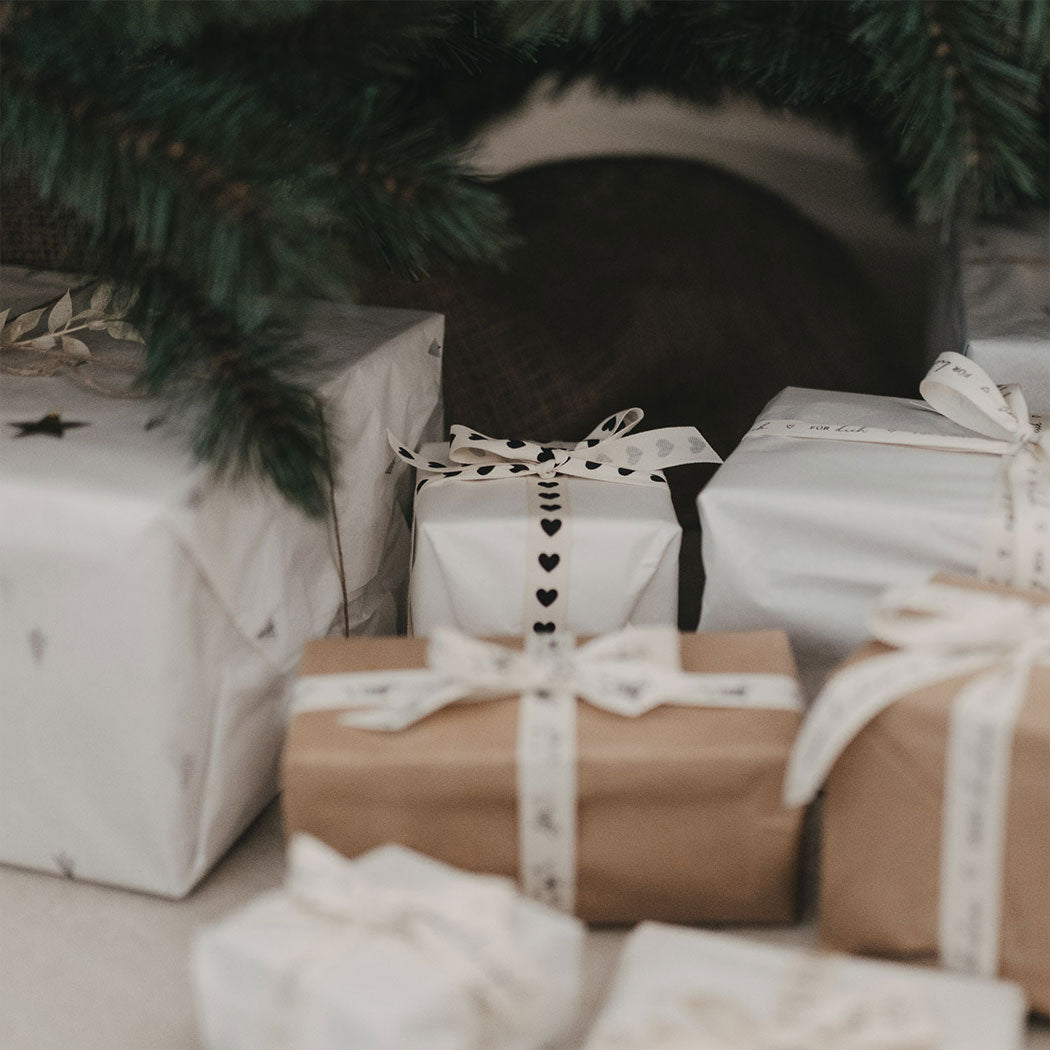 Geschenkband mit Dackelprint als Schleife an mehreren Geschenken, naturfarben