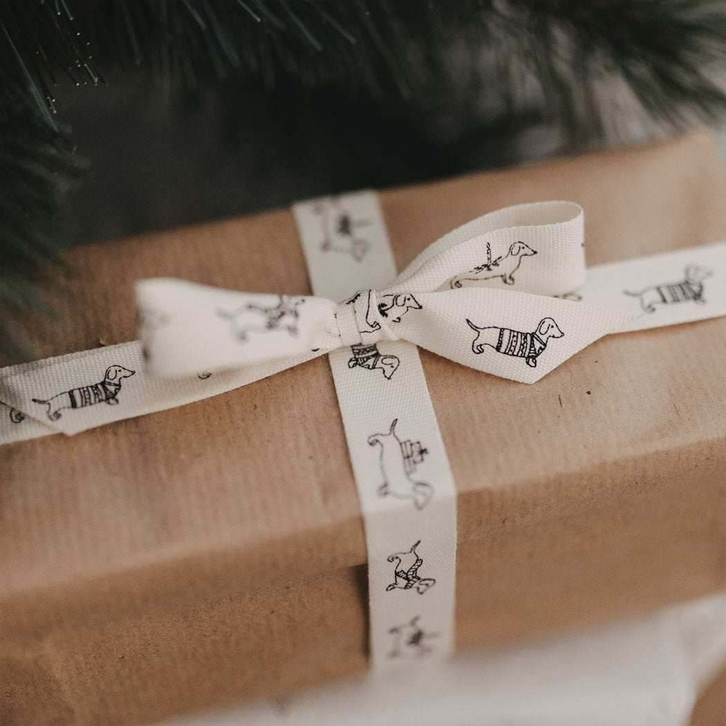Geschenkband: weißes Band mit Dackelmotiven, um ein Geschenk gebunden