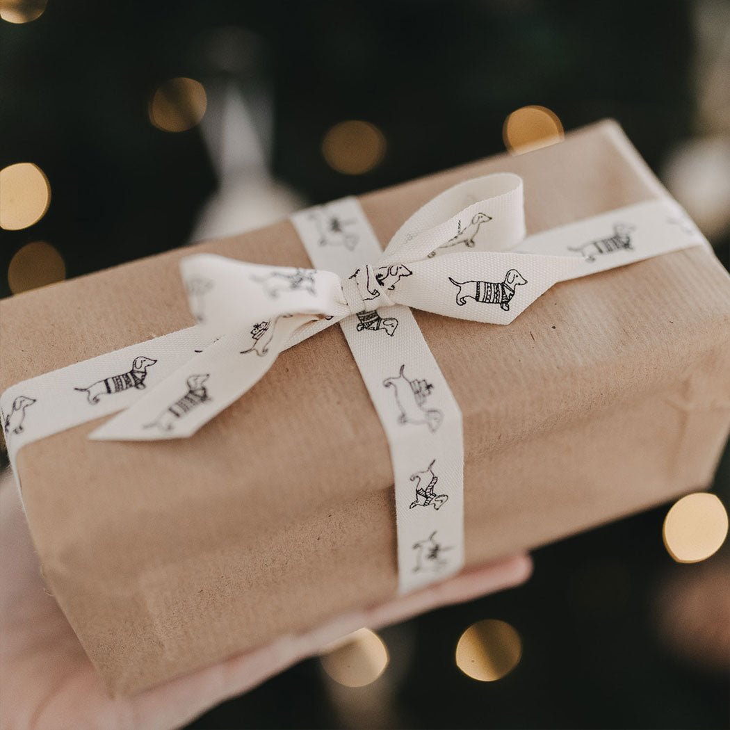 Geschenkband: weißes Band mit Dackelmotiven, Kreuzschleife auf braunem Geschenk