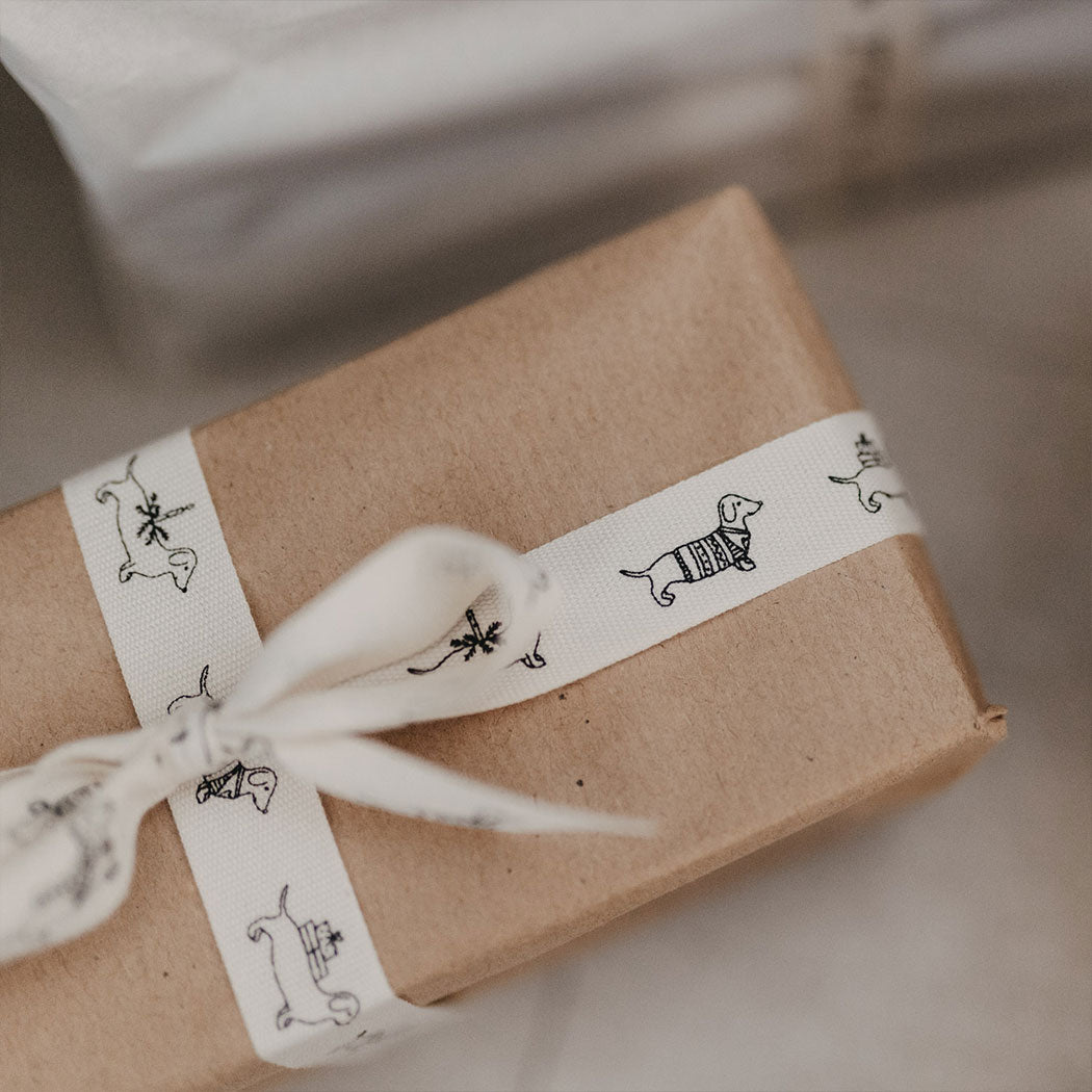 Geschenkband: weißes Band mit Dackelmotiven, Schleife am verpackten Geschenk