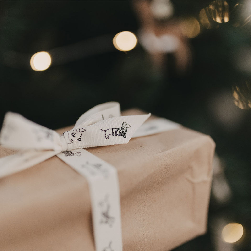 Geschenkband: weißes Band mit Dackelmotiven, Schleife auf braunem Geschenk