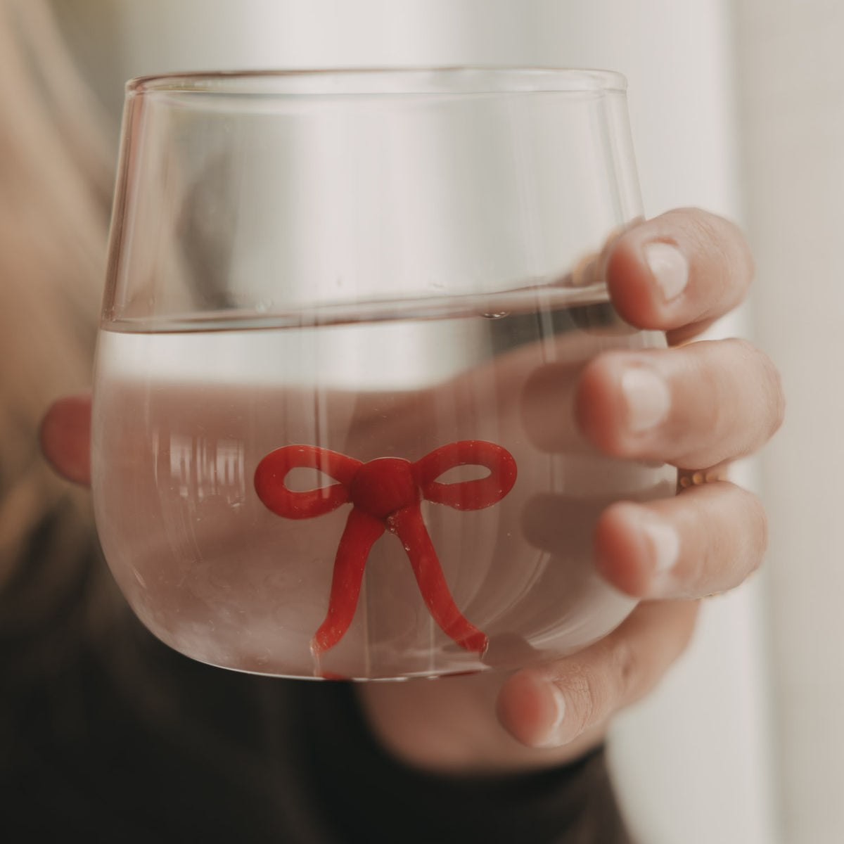 Figurglas mit roter Schleife, rundes Glas ohne Stiel, Nahansicht in Händen