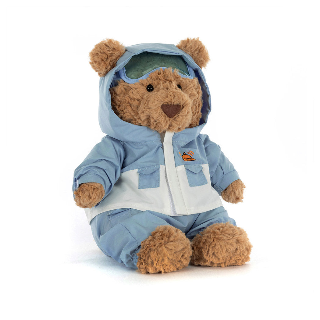 Kuscheltier Bär im blauen Skianzug mit Kapuze, brauner Pelz und Schnauze.