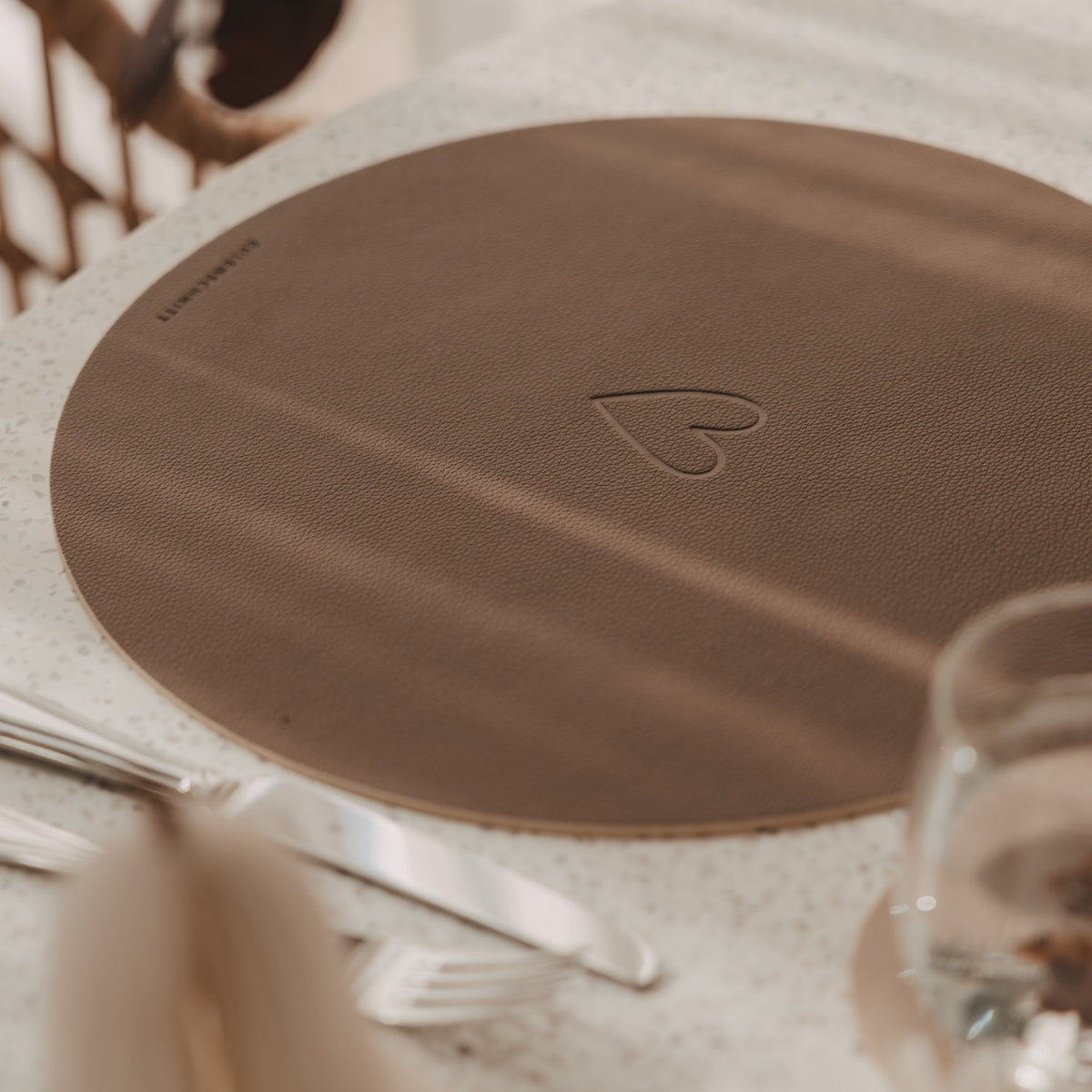 Rundes Platzset (Braun) mit Herzprägung, schräger Blick auf die Oberfläche.