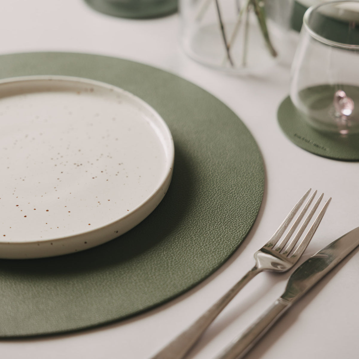 Grünes Platzset mit Sternprägung neben Besteck und Teller, runde Form