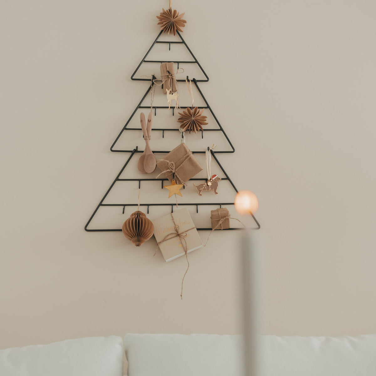 Tannenförmiger Adventskalender an der Wand mit Anhängern und Kerzenlicht