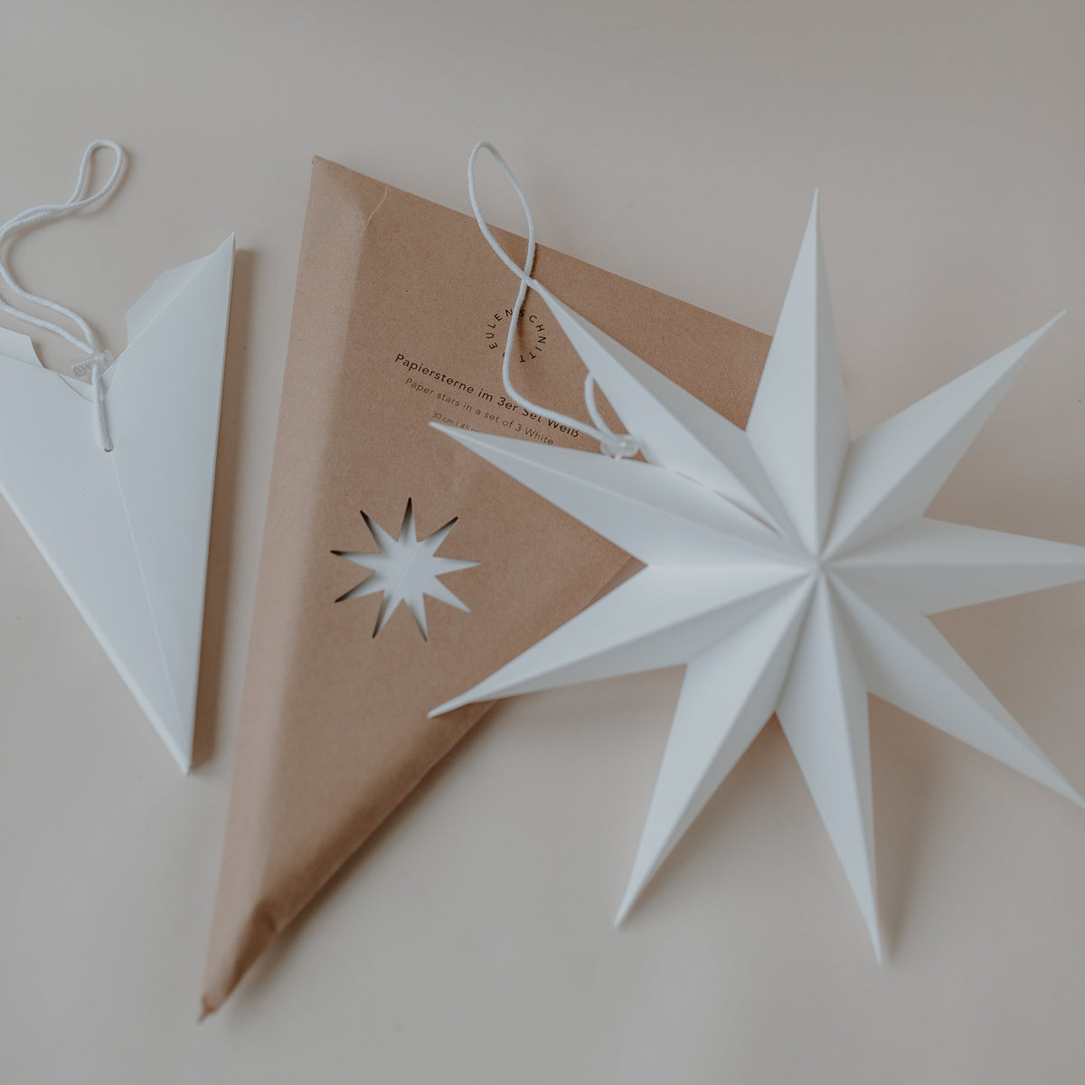 Weißer Papierstern mit Aufhängeschlaufe und kleiner Sternform, flach zum Aufhängen