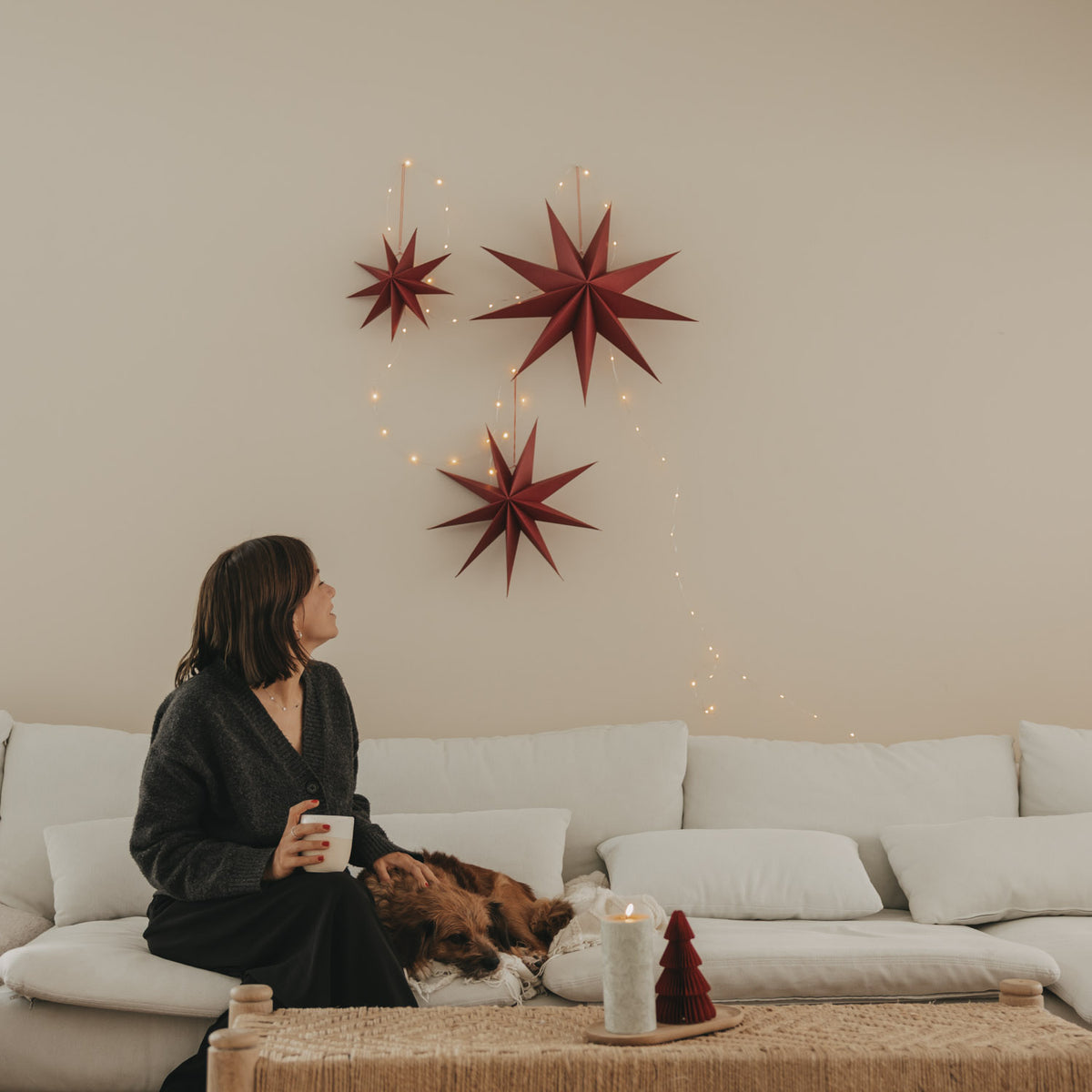 Rote Papiersterne im 3er-Set über dem Sofa, mehrere Sterne mit Lichterfaden