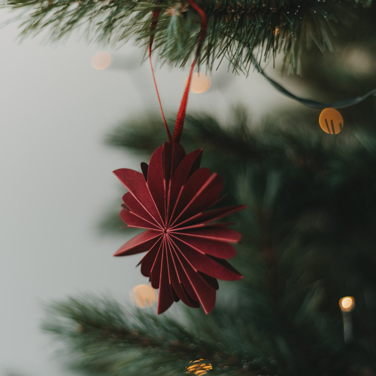 Dunkelroter Papieranhänger „Schneeflocke“ mit Aufhängeschlaufe am Weihnachtsbaum