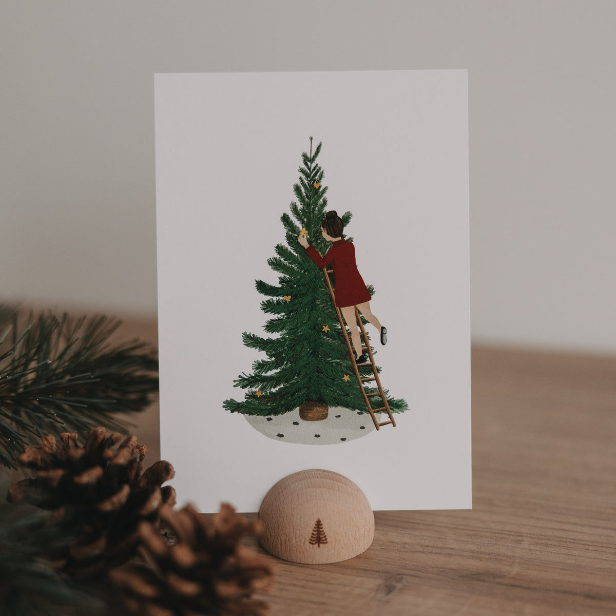 Aquarellkarte mit Mädchen am Leiter an grünem Tannenbaum, rote Kleidung, Weihnachtssterne