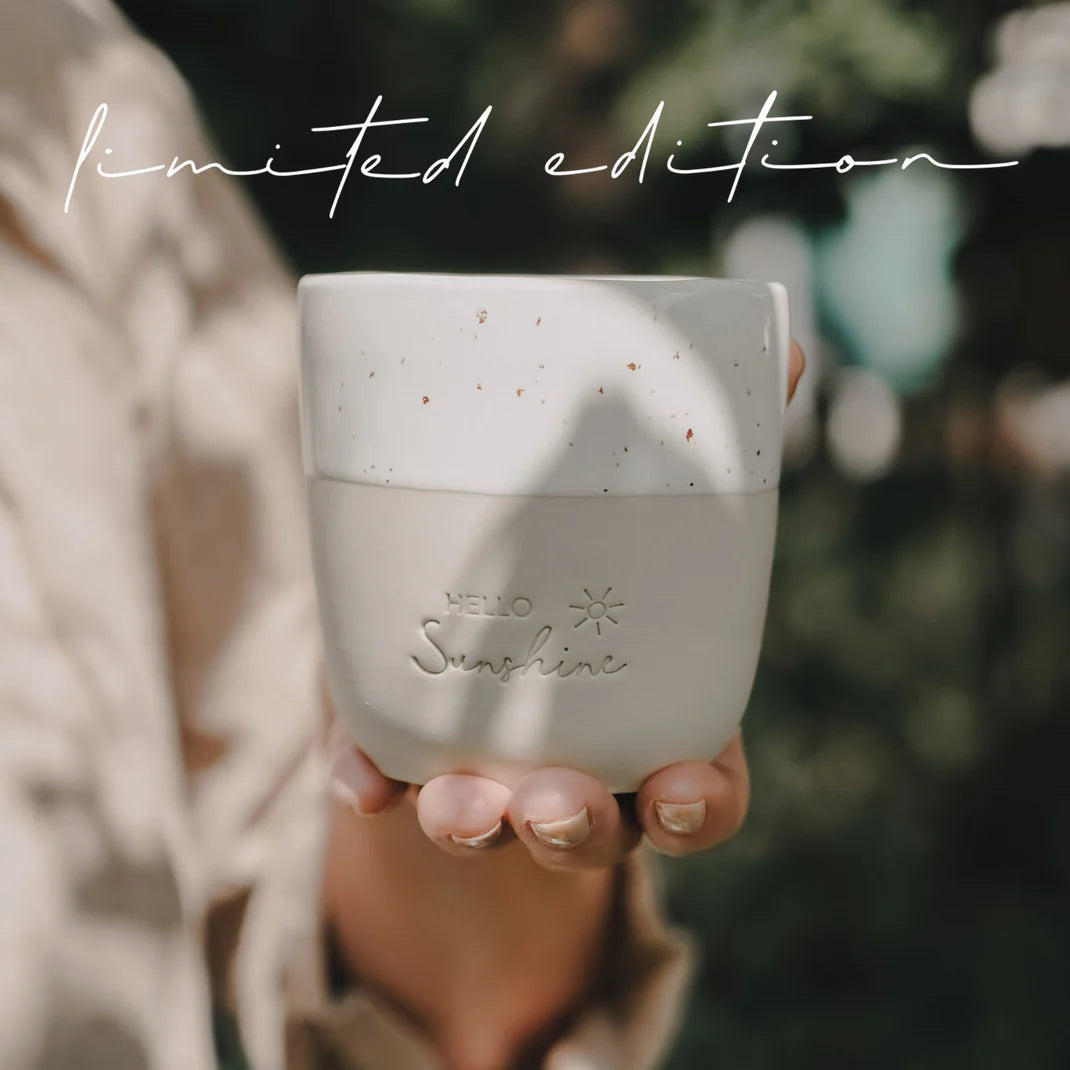 Naturfarbener Becher mit „Hello Sunshine“ und Sprenkelmuster, Hand von vorn