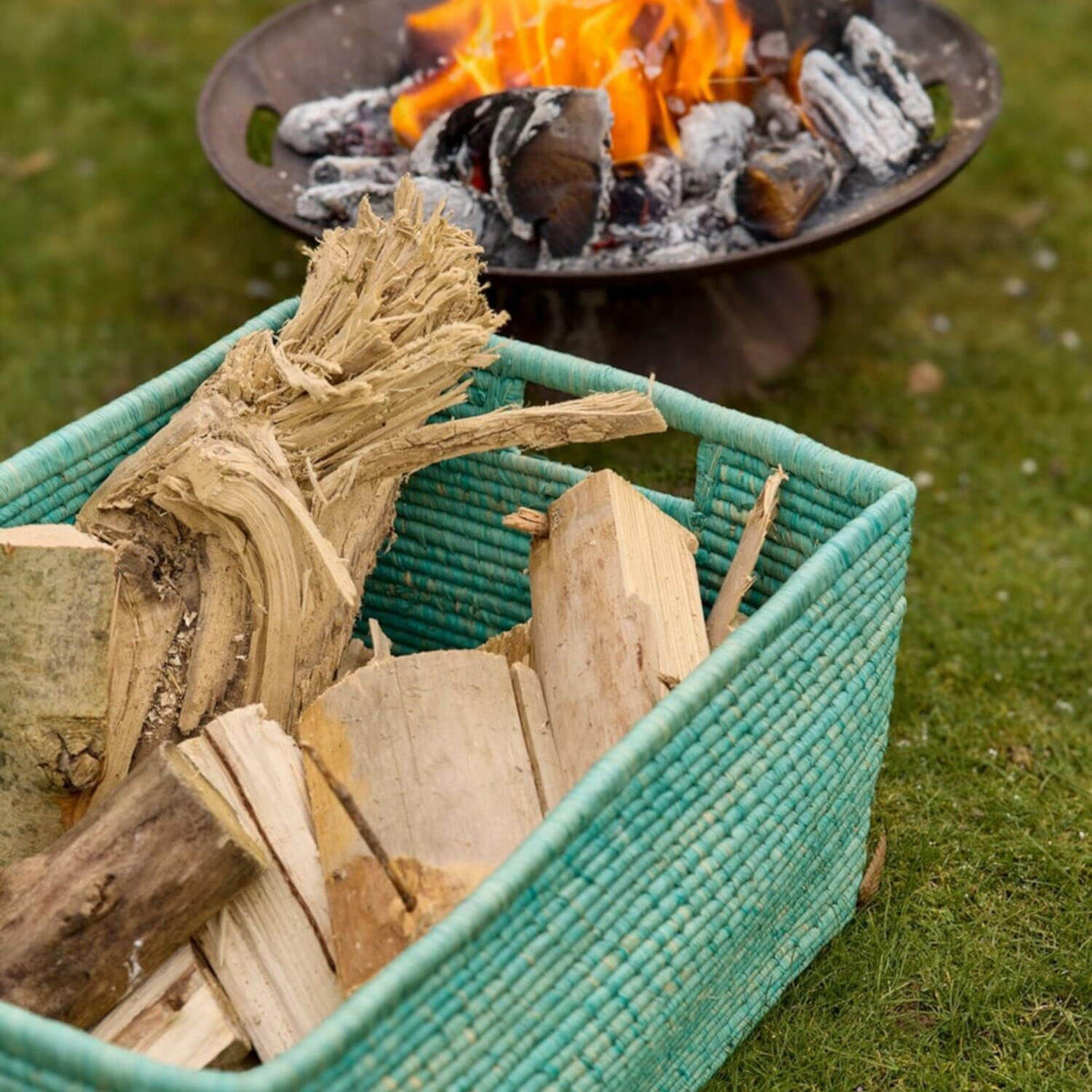 XL-Raffia-Korb in Grün mit Holzscheiten zum Befüllen am Feuerplatz