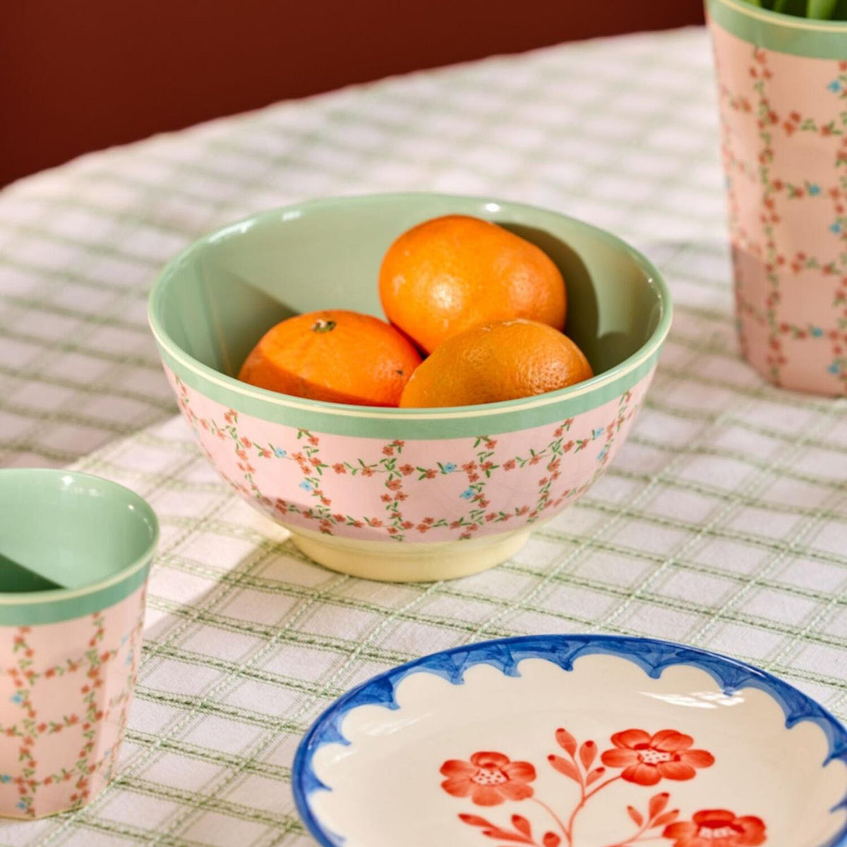 Melaminschale mit Blumenmuster und grünem Rand, gefüllt mit drei Orangen