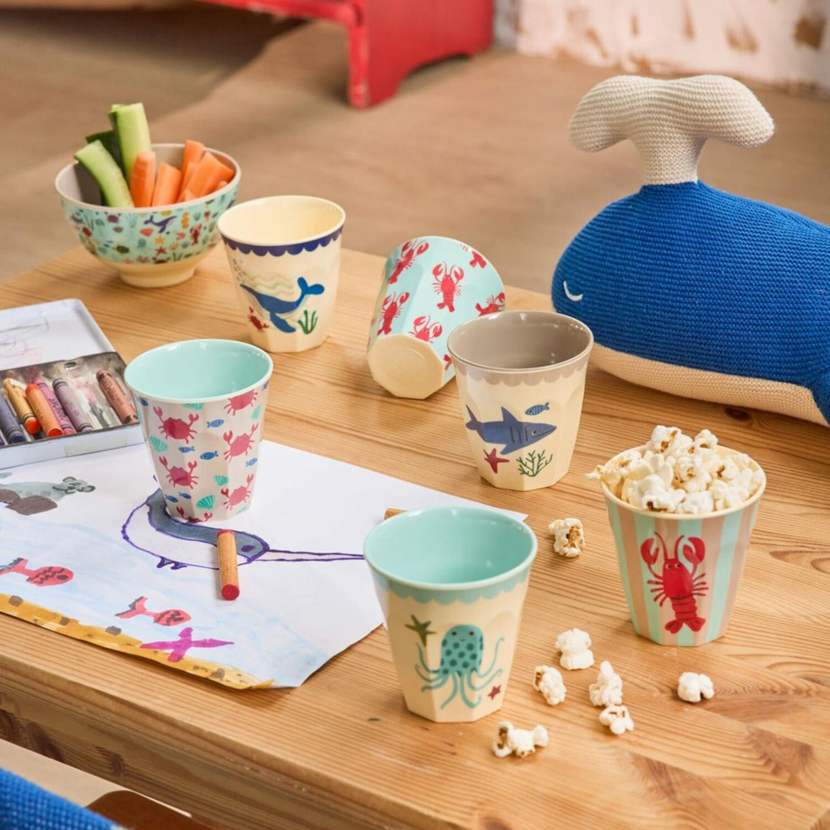 Mehrere Melamin-Becher mit Meeres-Tiermotiven auf einem Holztisch