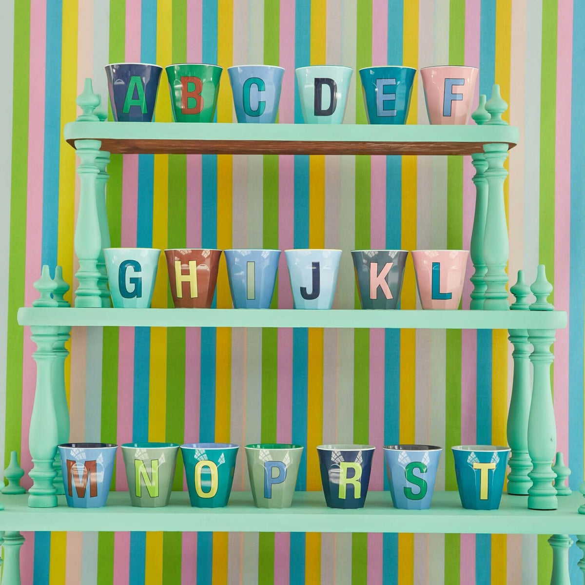 Bunte Melamin-Becher mit Buchstaben A bis F, in einer Regalreihe angeordnet