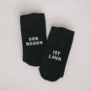 Schwarze Socken mit Schriftzug „DER BODEN“ und „IST LAVA“