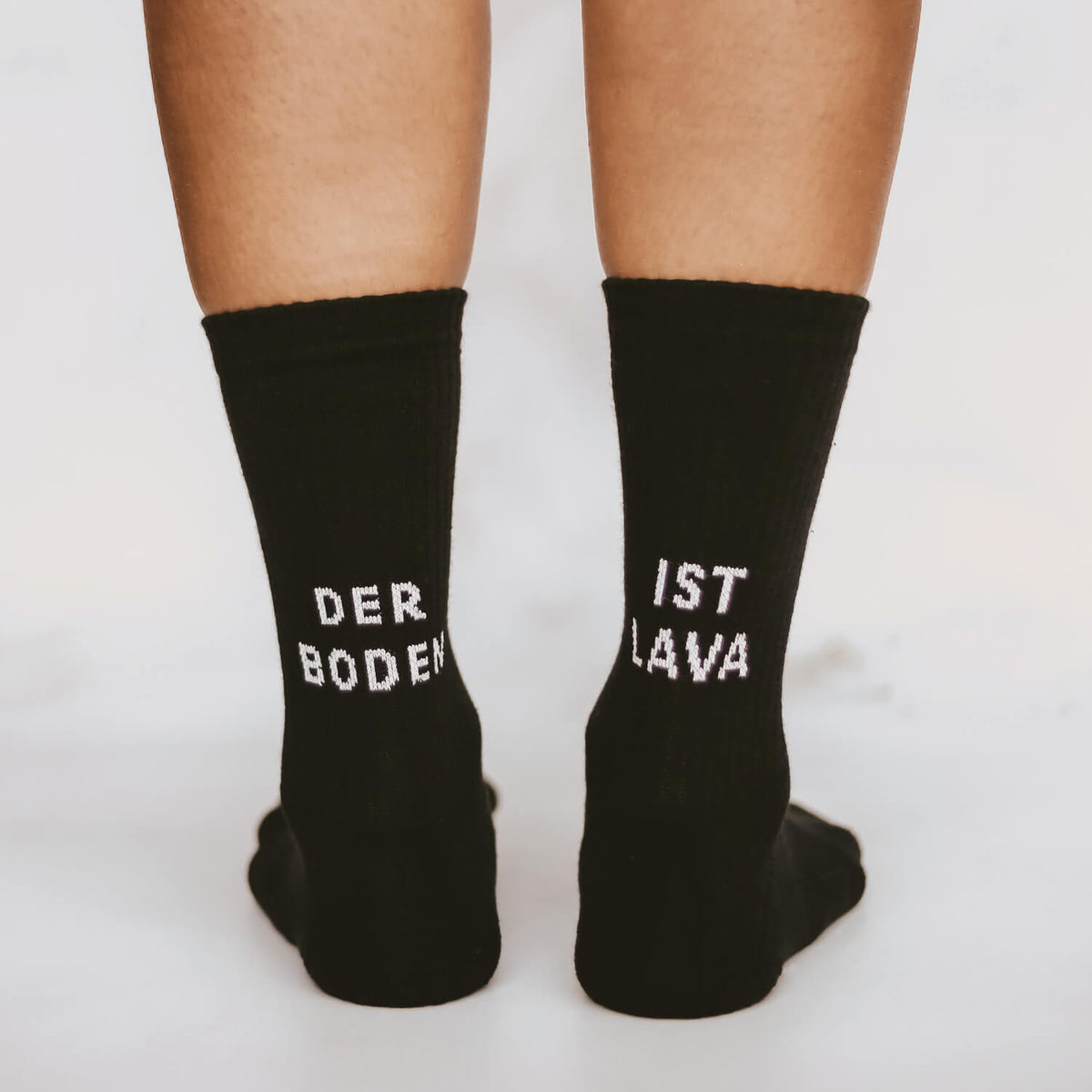 Schwarze Crew-Socken mit Schrift „DER BODEN“ und „IST LAVA“