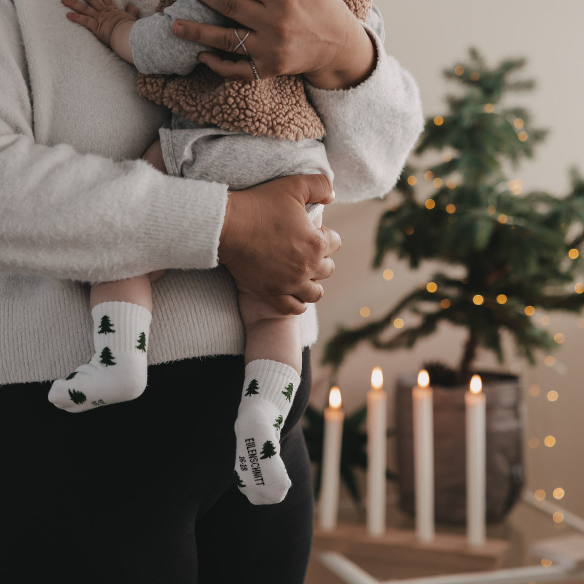 Babysocken mit weißen Socken und grünen Tannen, am Fuß getragen