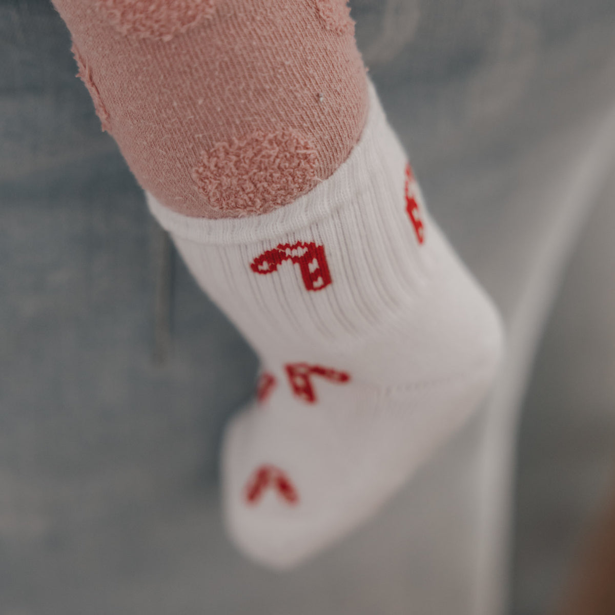 Babysocke in Weiß mit rotem Zuckerstangenprint, Blick auf das Bündchen
