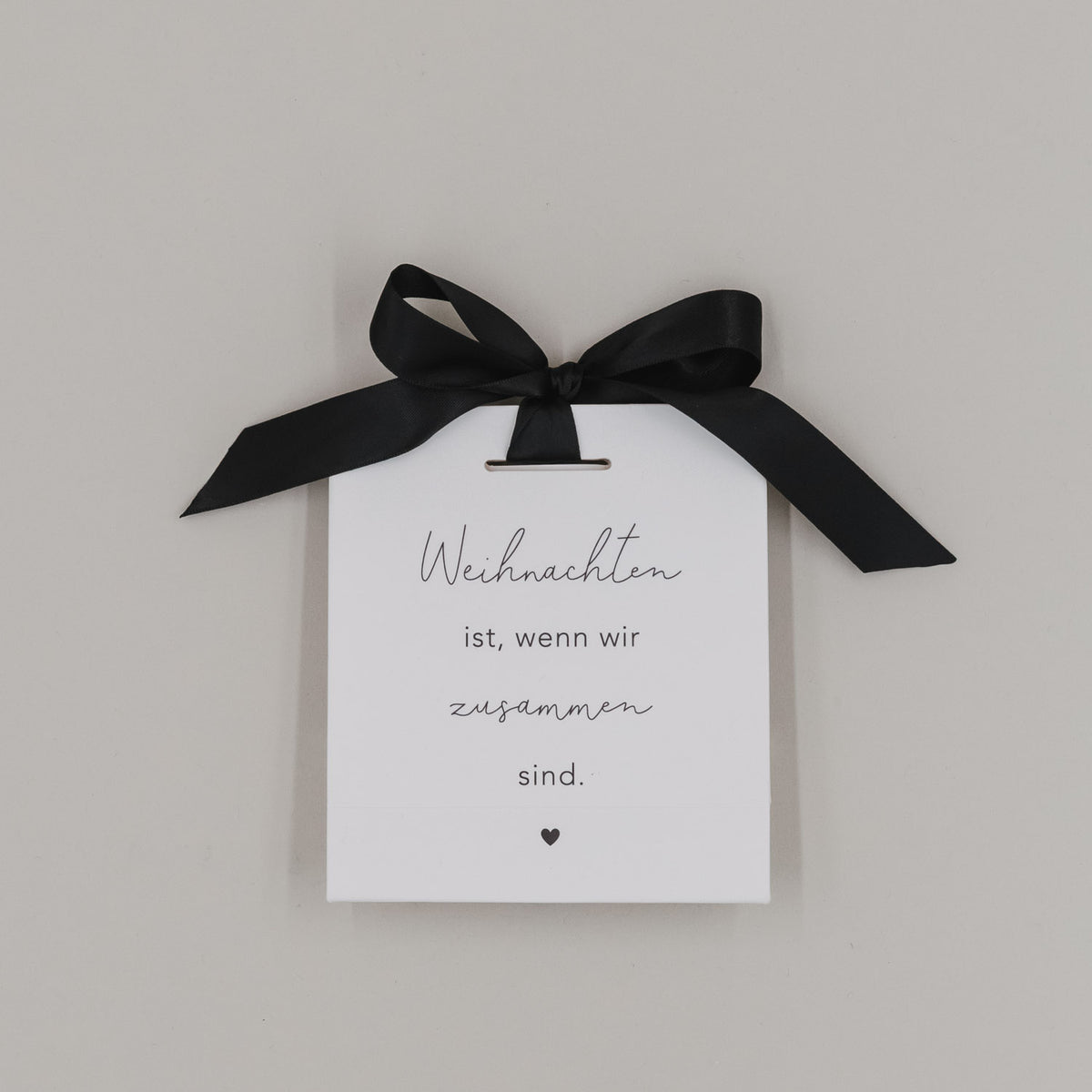 Weiße Geschenktüte mit schwarzer Schleife und Aufdruck „Weihnachten ist, wenn wir zusammen sind.“