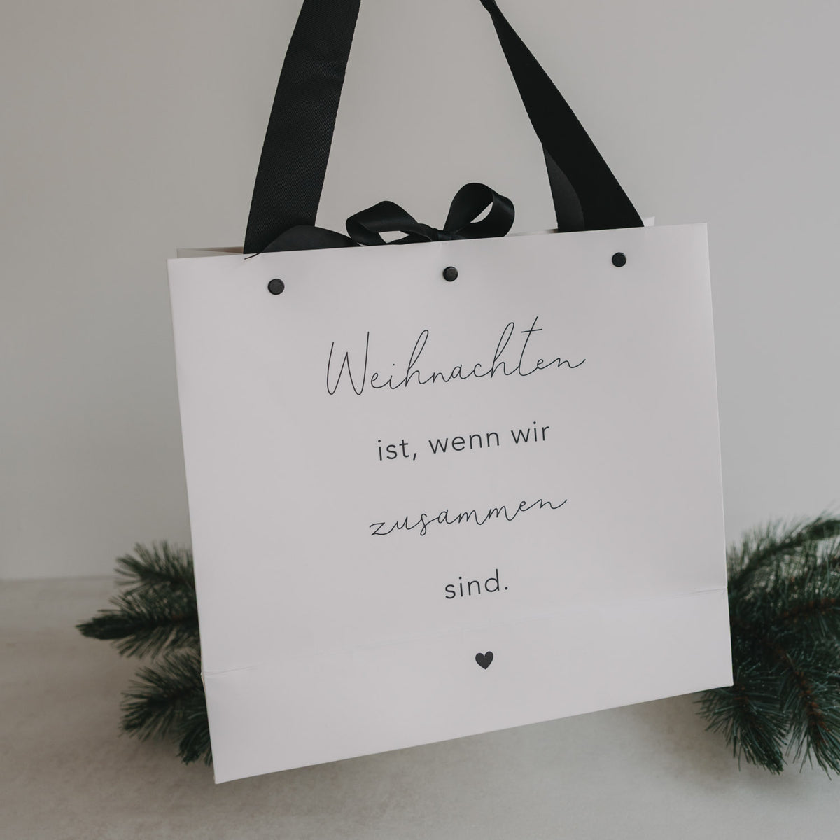 Weiße Geschenktüte mit schwarzem Band und Aufdruck „Weihnachten ist, wenn wir zusammen sind“