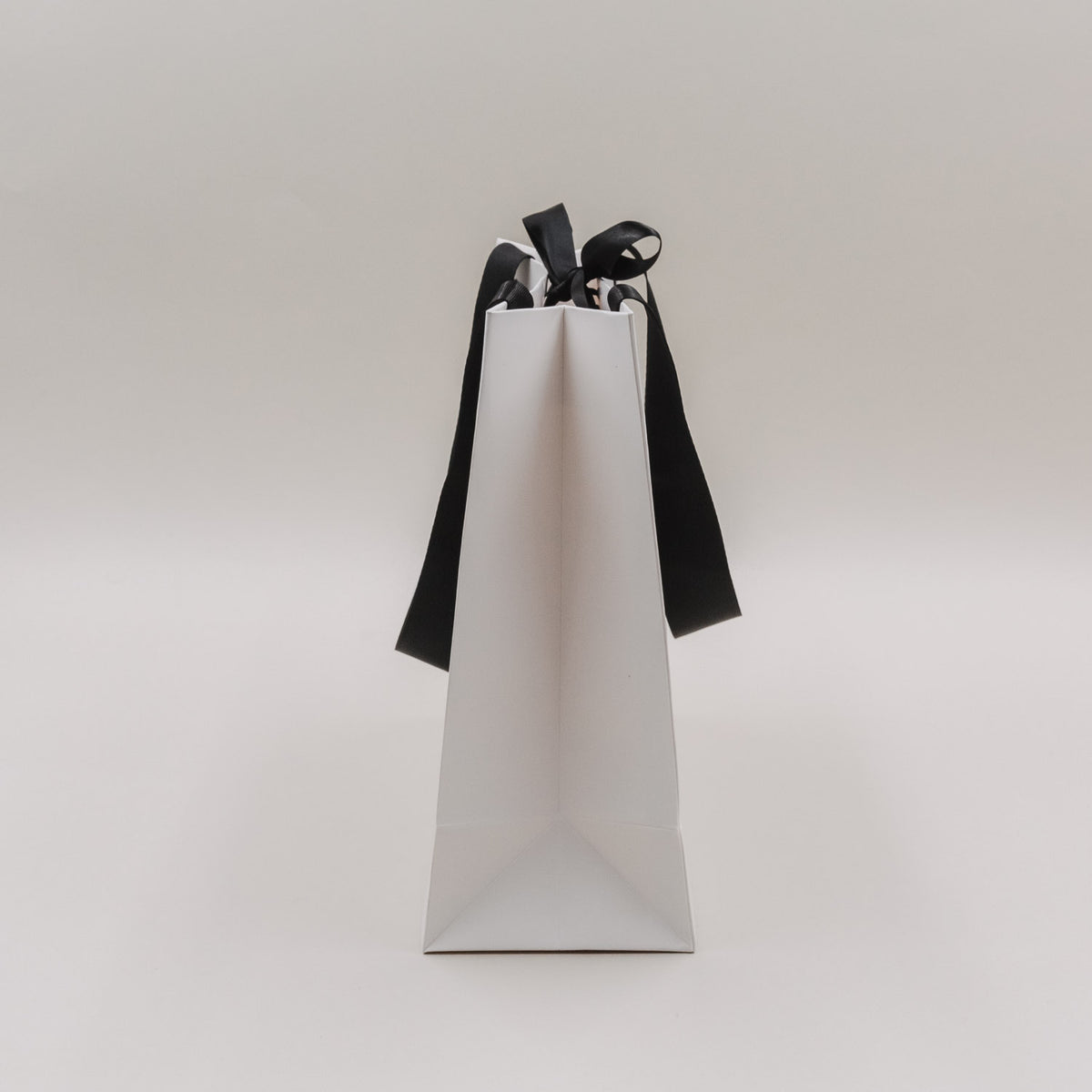 Weiße Geschenktüte (Medium) mit schwarzen Schleifen, Schriftzug „Weihnachten ist…“