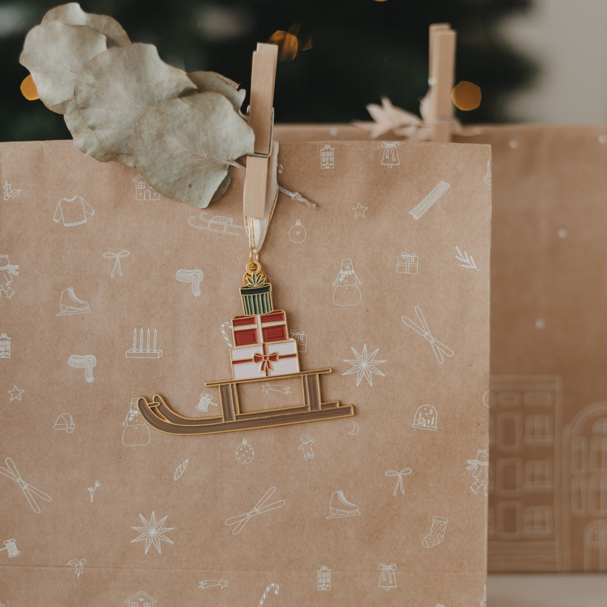 Braune Papiertüte mit Musterlinien und Anhänger aus Holz mit Schlitten-Motiv