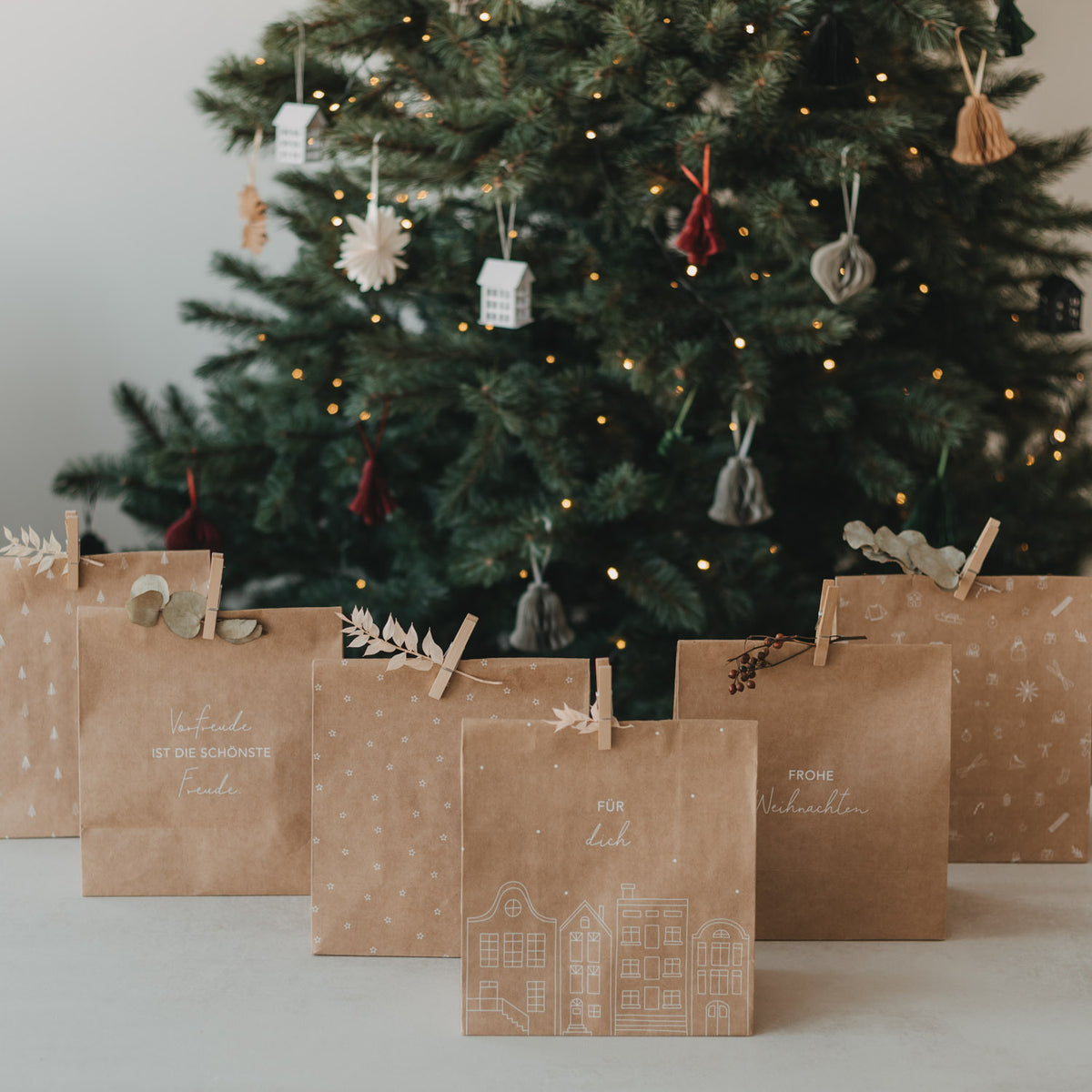Mehrere braune Papiertüten mit weißen Weihnachtsmotiven, über der Kordel aufgehängt