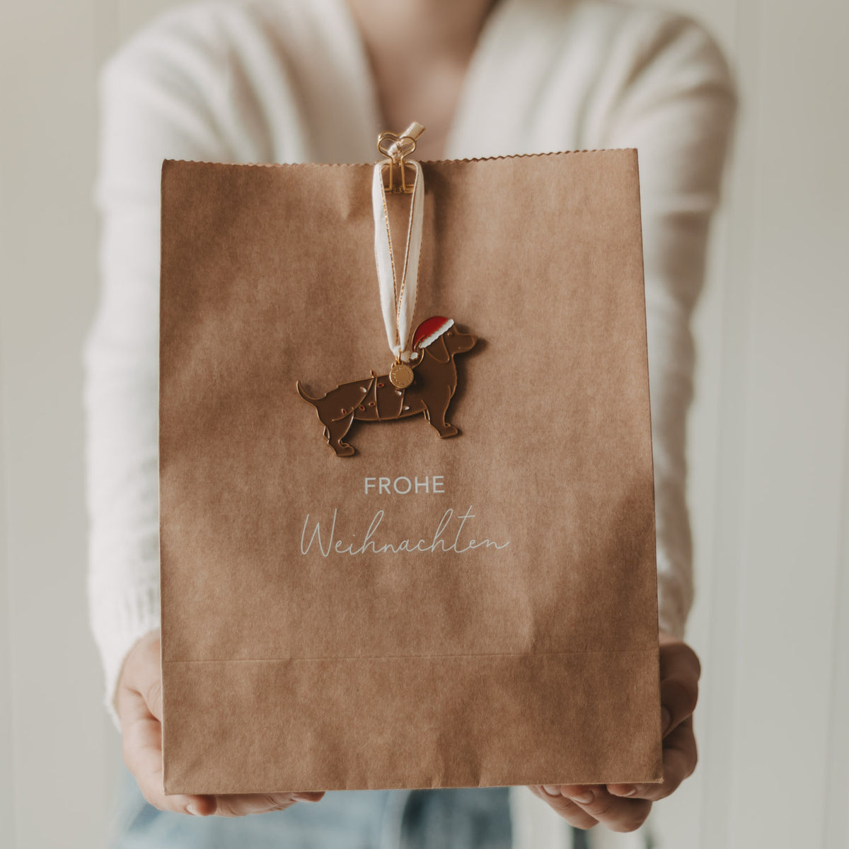 Braune Papiertüte mit Hund-Emblem und „Frohe Weihnachten“-Aufdruck, mit Bandgriff