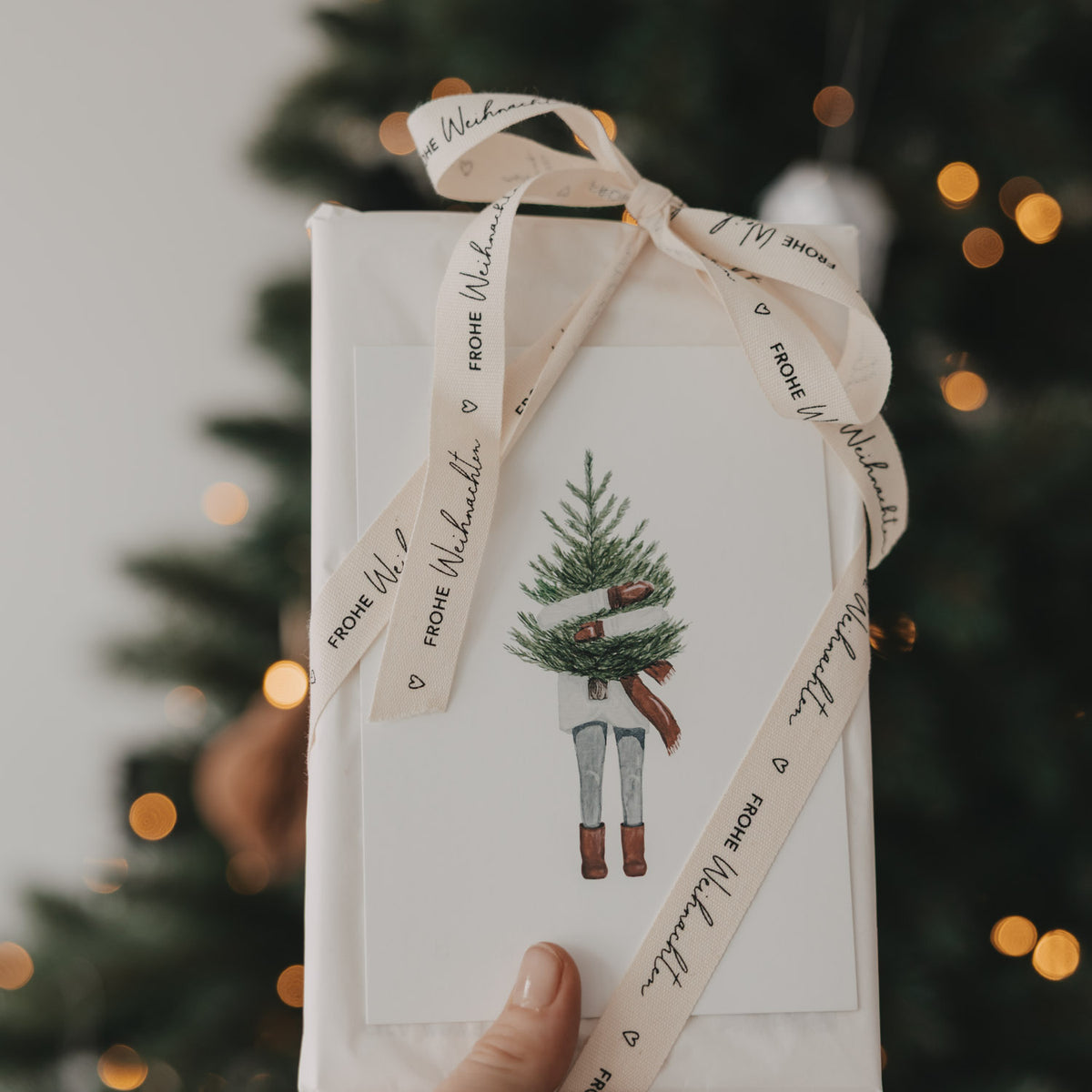 Geschenkband „FROHE WEIHNACHTEN“ mit Weihnachtsmann-Illustration am Geschenk